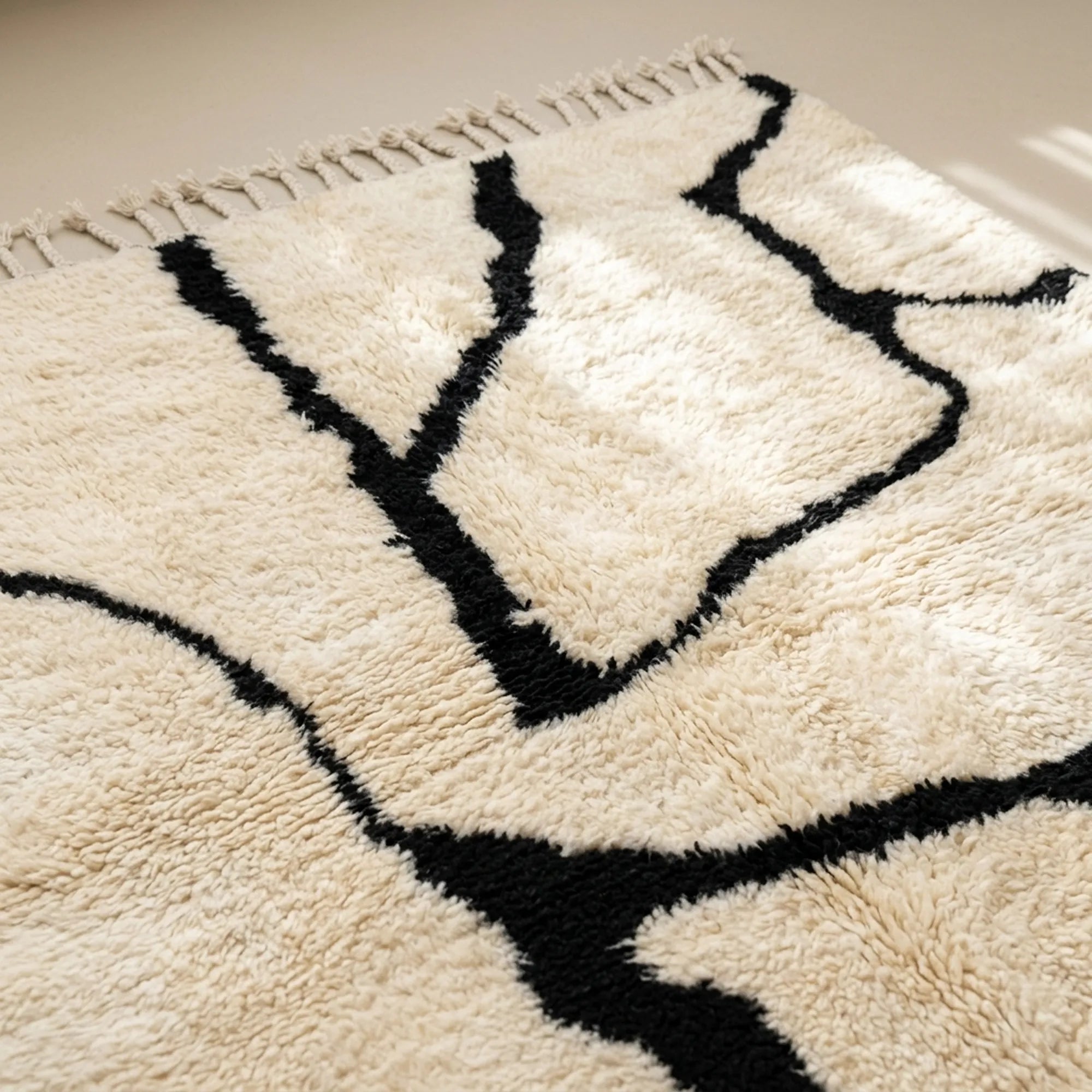 Angled view of the Inur warm ivory and black Beni Ourain rug showing the complete branch line design.