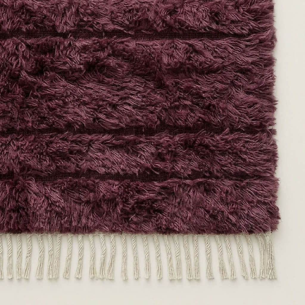 Bottom edge detail of wine Beni Ourain rug showing cream wool fringe against dark pile