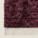 Detail shot of wine Beni Ourain rug corner and fringe, showing cream knotted fringe edge